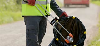 Picking up litter with a litter picker and placing into waste bag